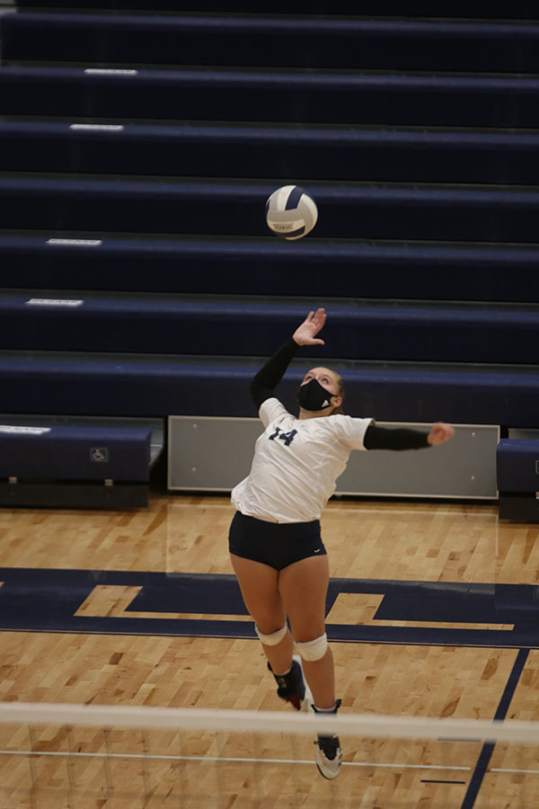 Jumping, junior Sydney Fiatte serves the ball over the net to the opponent.