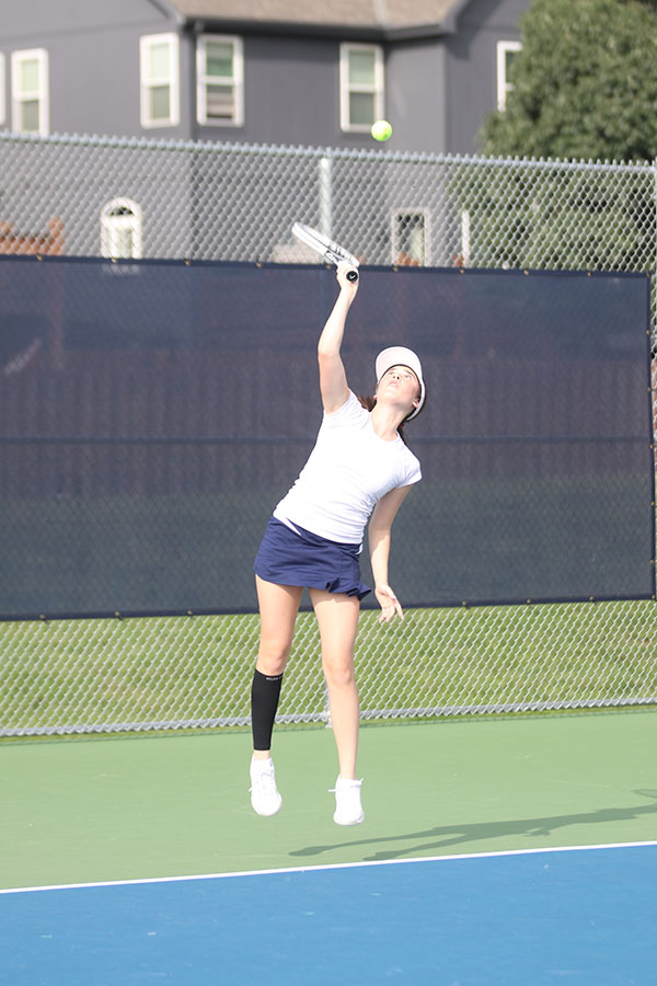 Reaching up, junior Eden Schanker serves to her opponent.
