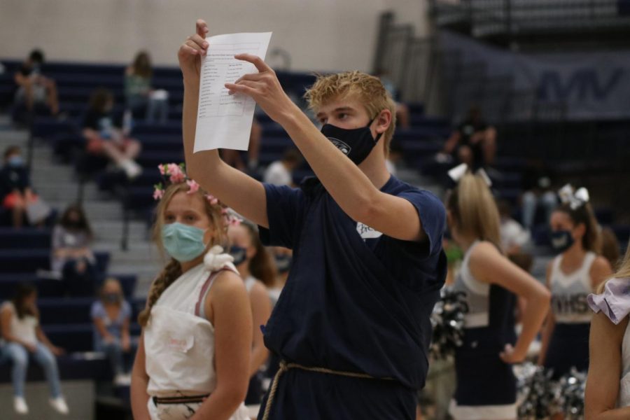 Preparing the freshmen to learn the fight song, junior Bret Weber holds up the paper that has the lyrics for them to read.