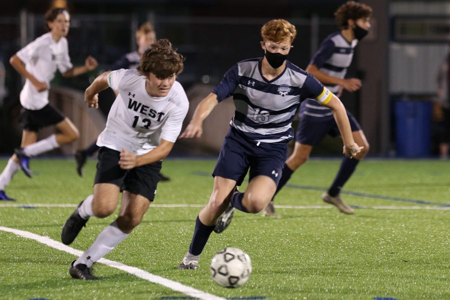 Next to an opponent, sophomore Owen Peachee races to the ball. The boys soccer team tied 3-3 against Shawnee Mission West while playing at home Thursday, Sept. 24.