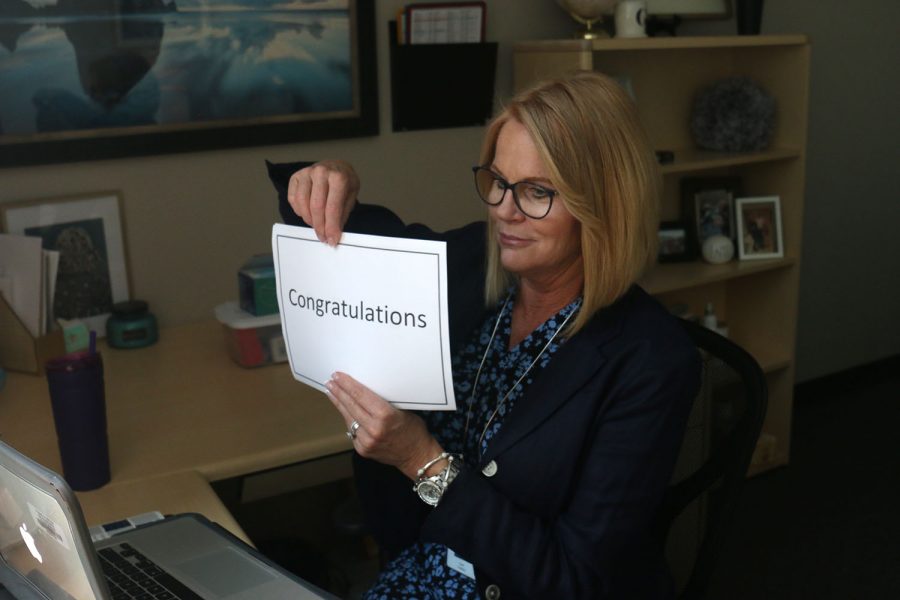To honor students named National Merit Scholarship semifinalists, principal Dr. Gail Holder holds a sign reading “Congratulations” on a Zoom call Wednesday, Sept. 9.
