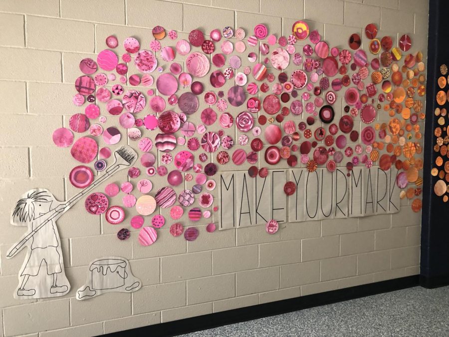 Using her students’ creative talent, art teacher Mrs. Strong displays their “Dot Project” in the main hall.