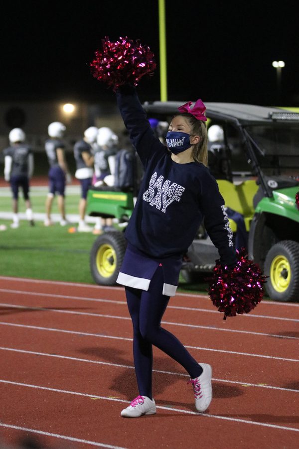 Poms up, freshman Claire Moberly cheers on the team.
