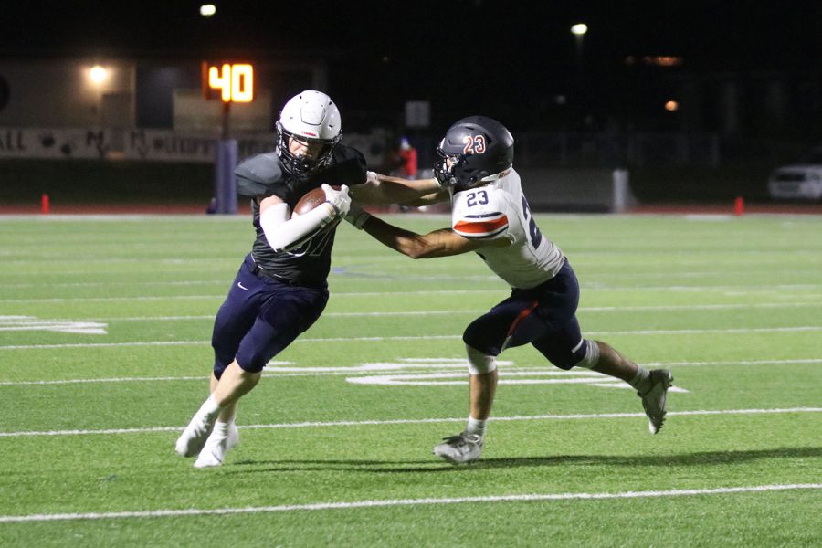 Holding off the defense, junior Jared Napoli focuses on gaining a few more yards.
