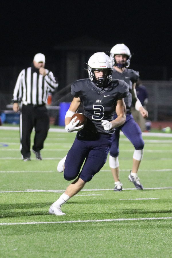 Running, senior Jacob Hartman makes his way down the field while holding onto the ball.
