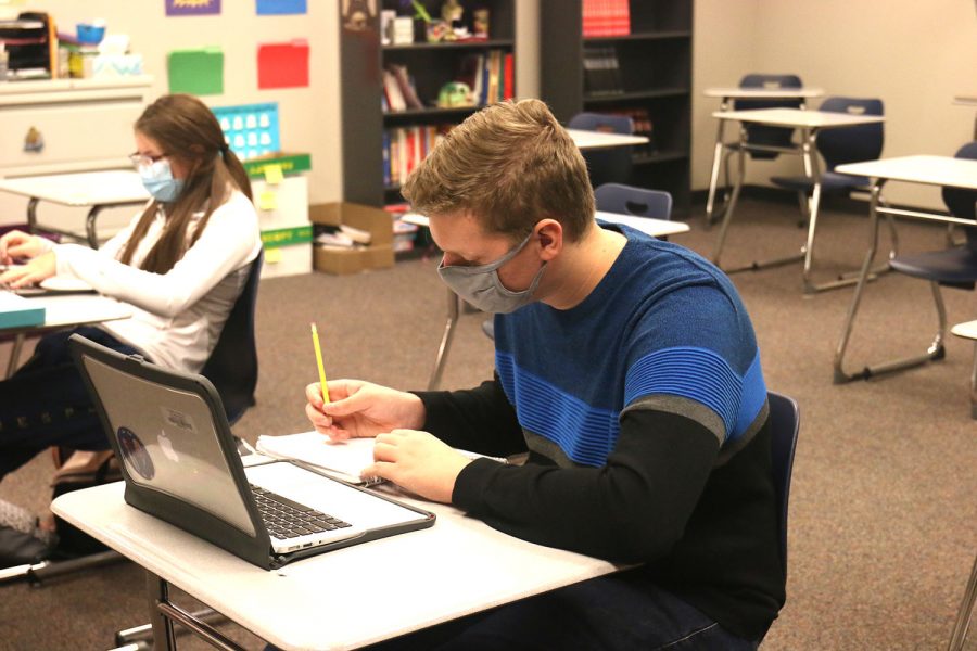 While wearing a mask and practicing social distancing in the classroom, Junior Ben Baumgart works on his in-class french assignment on Thursday, Oct 1. 