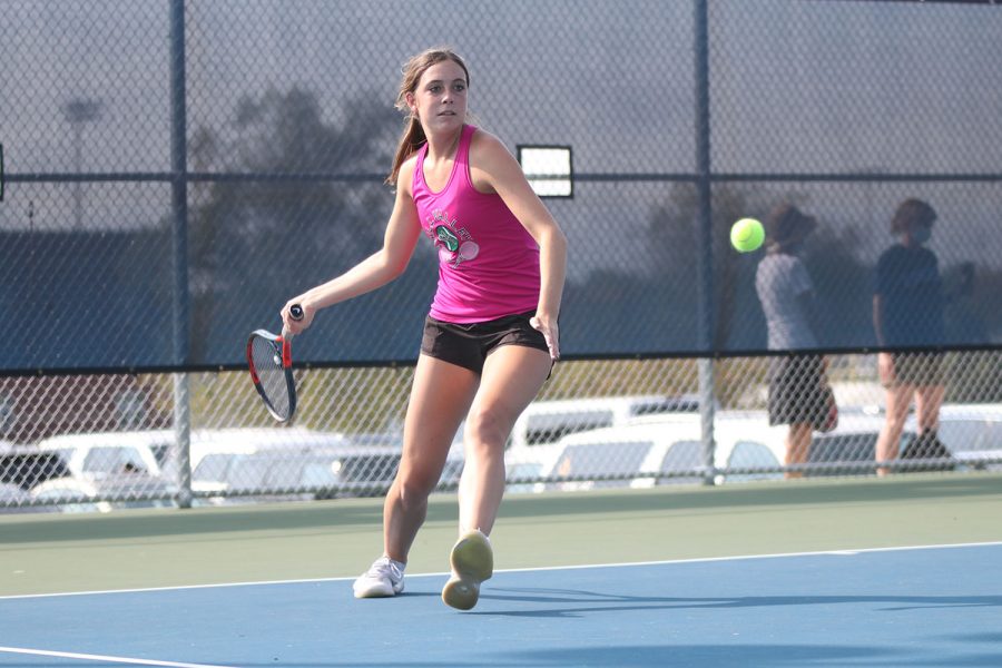 With her eyes on the ball, senior Sophie Lecuru steps forward with her racket to hit the ball at tennis regionals Saturday, Oct. 10. The girls tennis team placed third overall and Lecuru is advancing to play at state.