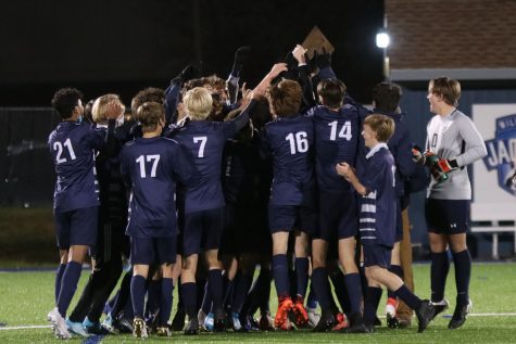 Regional championship award in the air, the boys soccer team celebrates their victory together.