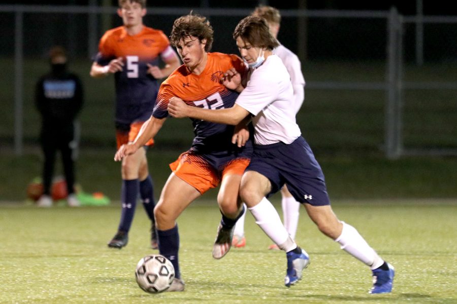 With an opponent at his side, junior Ryan Wingerd attempts to gain possession of the ball during the game against Olathe East Friday, Oct. 2. The Jaguars trailed Olathe East 2-0.