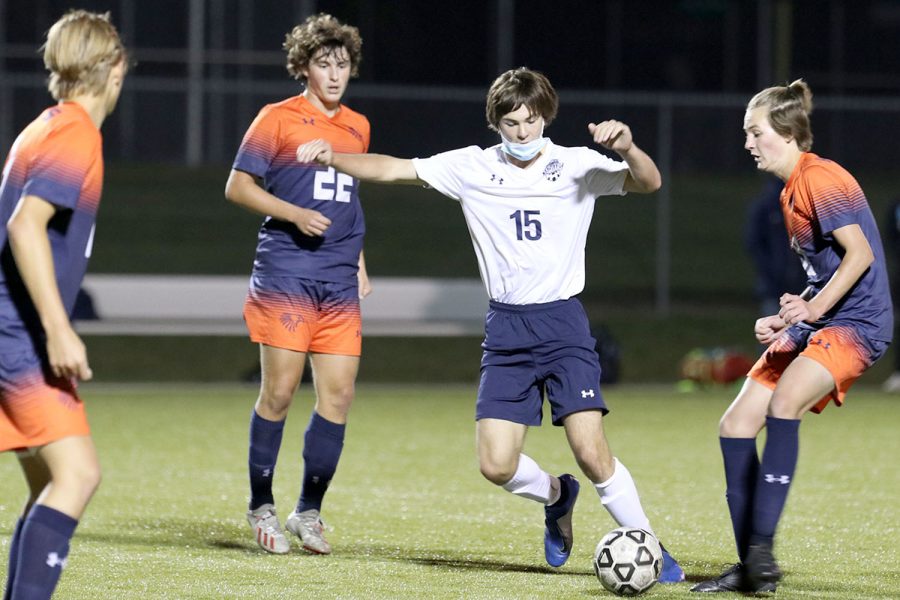 With three opponents surrounding him, junior Ryan Wingerd maneuvers the ball toward his teammates.