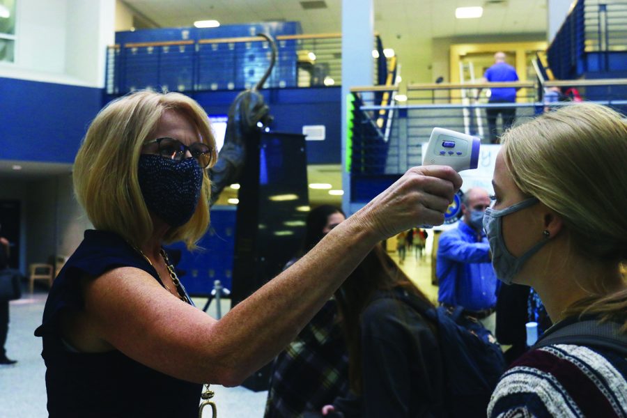 With a thermometer in hand, principal Dr. Gail Holder checks a students temperature before school Monday, Sept. 28.