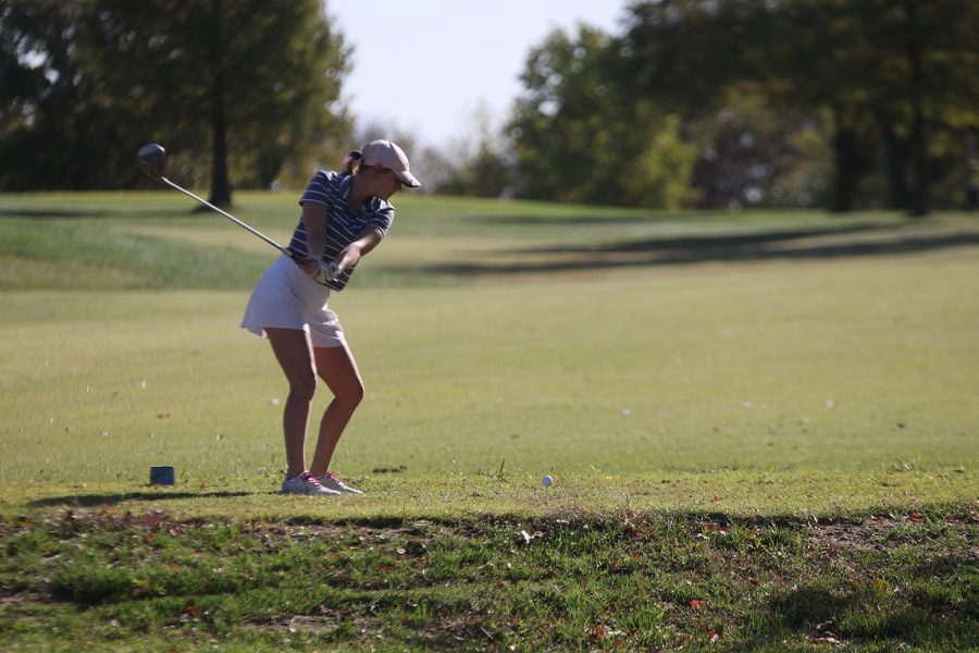 Golf club above her head, senior Ava Van Inwegen prepares to hit the golf ball.
