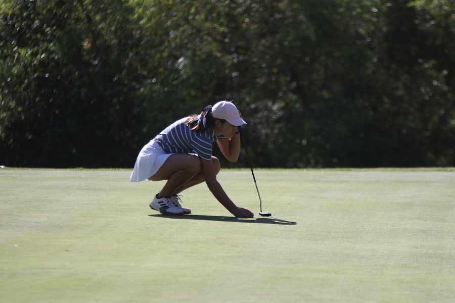 Squatting down, junior Libby Green places her ball on the ground.
