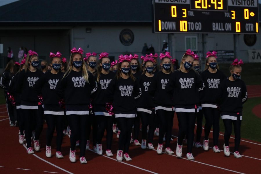 With hands behind their back, the cheerleaders walk down the track to get ready to cheer for the game.