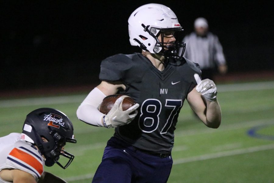 With the ball cradled in his arm, wide receiver Jared Napoli runs to the end zone while a player from Olathe North tries to tackle.