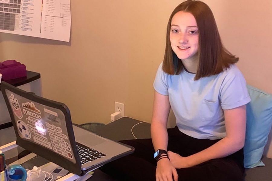Getting ready to start her first day of school under the new optional-remote learning model provided by the district this year,  Freshman Emma Clement smiles next to her computer and desk setup on Wednesday, Sept. 9.