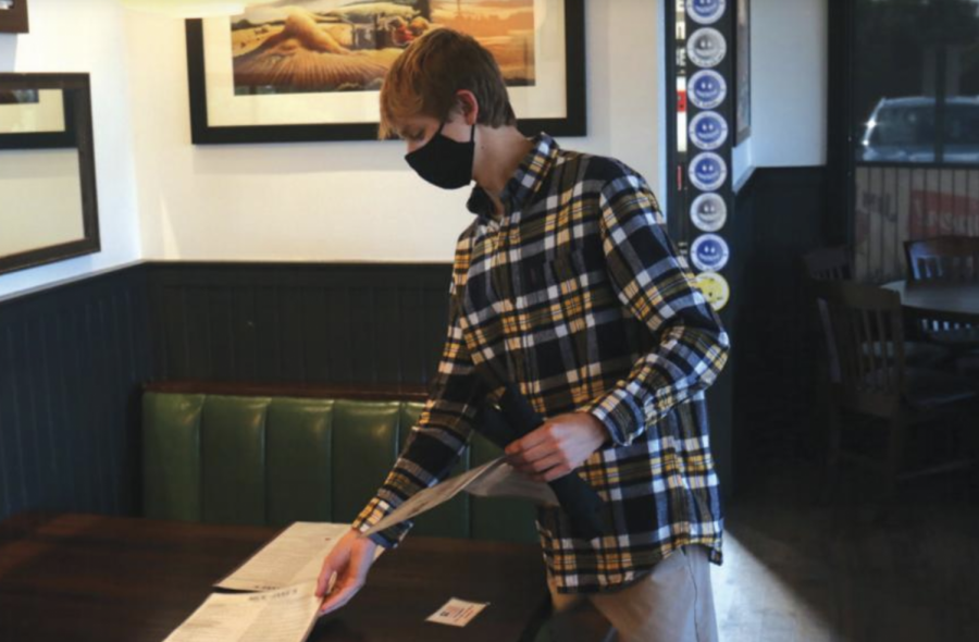 Making sure the menus are arranged correctly, senior Kyle Moylan sets a table at Nick and Jake's.