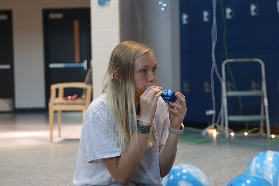 Blowing up a balloon, senior Taylor Sitzman prepares to hang them on the wall. 
