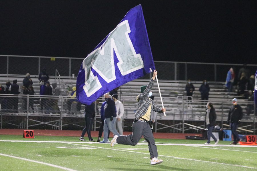 Holding the flag, senior Nate Milberger runs across the field at the conclusion of the game.
