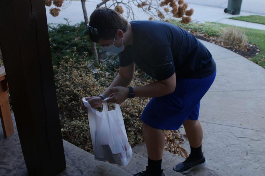 Donated food is collected from a donor’s porch by NHS member senior Tommy Sellen to be donated to the Shawnee Community Services Center, where food collected during the drive will be distributed to community members in need of food for Thanksgiving.
