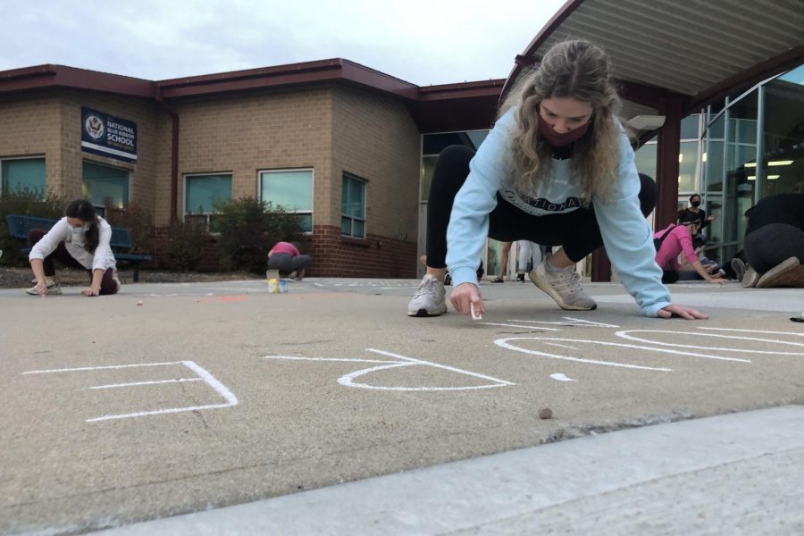 Crouched over her art, senior Tyler Bret draws with chalk at Clear Creek Elementary for NHS hours. 