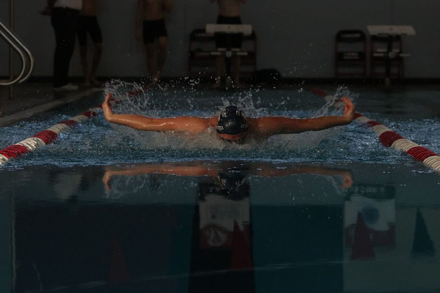 Arms extended in a butterfly stroke, senior Noah Collins swims against his competitors Saturday, Dec. 5. 