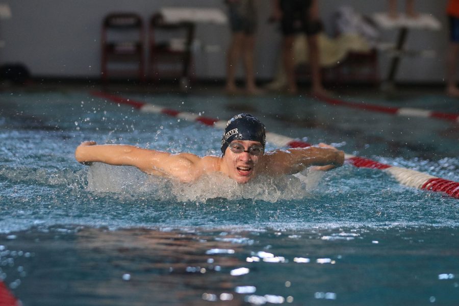 Arms above the water, senior Mason Davis competes swimming the butterfly. 
