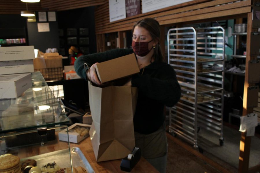 Working at McLain’s during the pandemic, senior Kenzie Harris bags food for a customer that she just prepared along with her coworkers.
