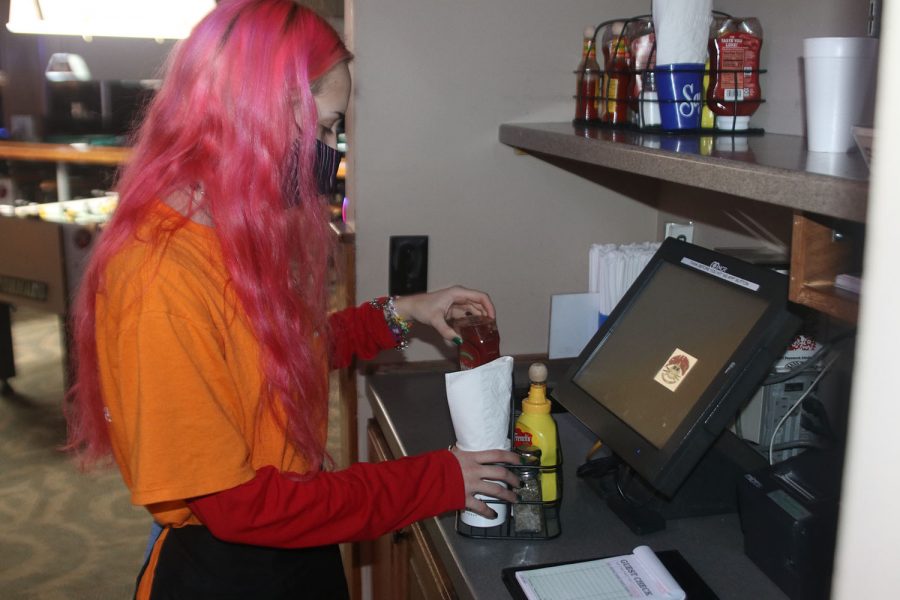 Due to COVID-19, restaurants have amplified sanitation. Sharks Bar and Grill employee Emily Smith put together a condiment caddy after the condiments had been disinfected on Monday, Nov. 11. 