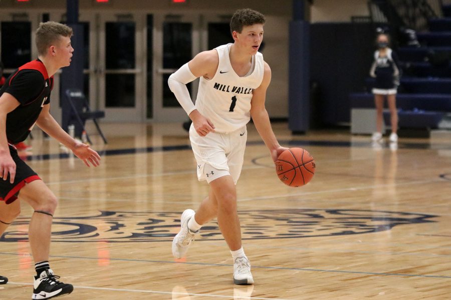 Dribbling the ball, senior Nick Mason looks for an open teammate to pass the ball to Friday, Jan. 15. The team played Lawrence High where they lost 57-31. 