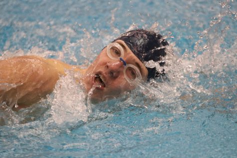 Taking a breath, junior Brendan Akehurst swims the 100-yard freestyle, finishing with a time of 1:18.50. 