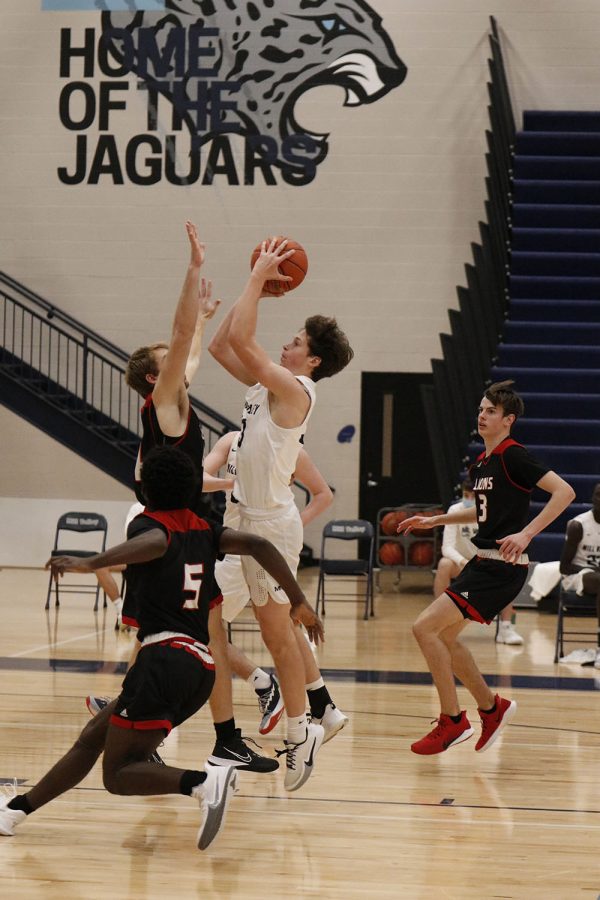 With the opposing team surrounding him, sophomore Dylan Blazer goes up to shoot the ball. 