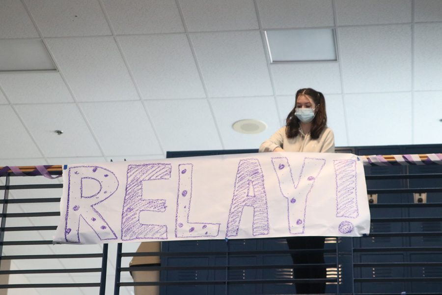 Placing the sign, Sophomore Grace Brookshire places tape onto the sign so it doesnt fall. 
