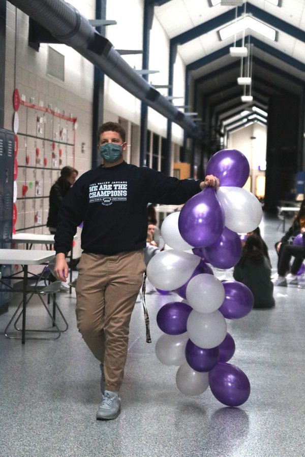 With a long row of balloons, junior Declan Taylor drags a row of balloons behind to hang up.
