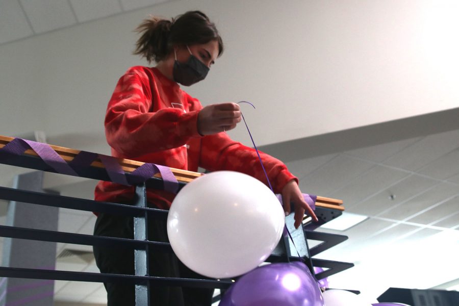 At purple bomb, junior Logan Pfeister hangs and positions the balloons to the railing.
