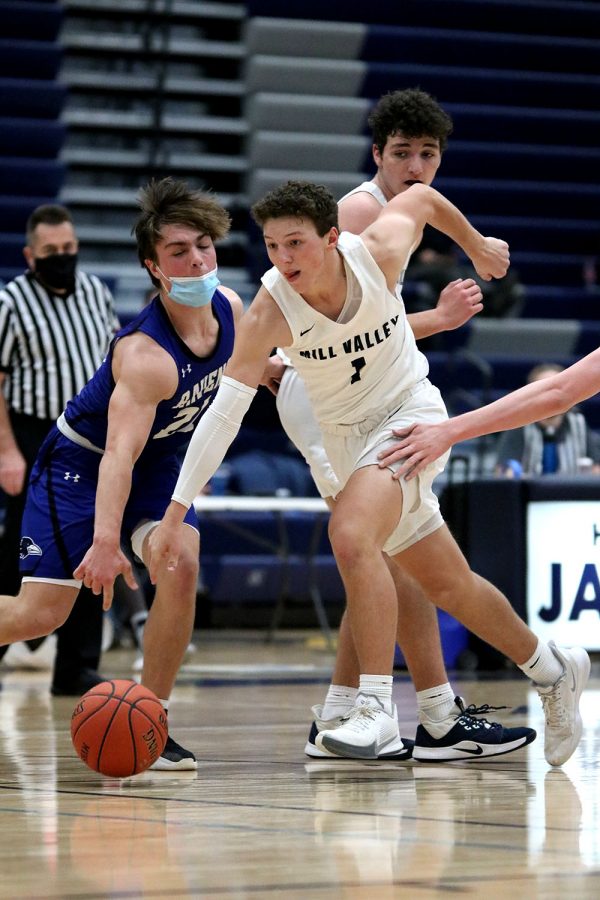 Dribbling the ball, senior Nick Mason advances towards the basket while surrounded by his opponents. 