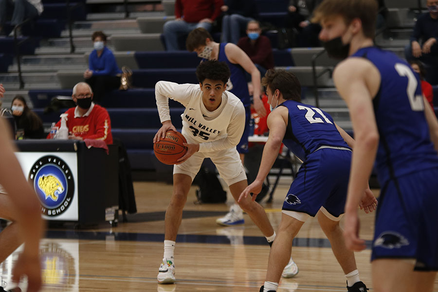 With possession of the ball on Friday, Feb. 5,  junior Adrian Dimond scans the court for a teammate who had the opportunity to receive the ball. The team played Olathe North west and lost 59-55. 