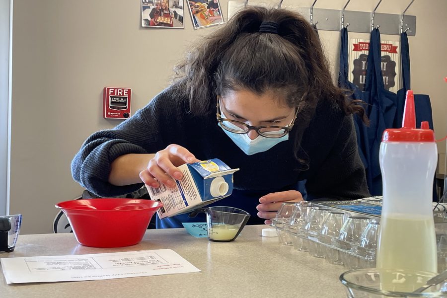 Focusing on measuring correctly, junior Leila Garcia pours milk into a measuring cup.