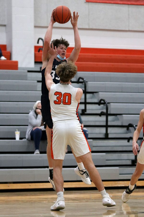 Leaping off the ground, sophomore Dylan Blazer passes the ball over his opponents to his teammate. 