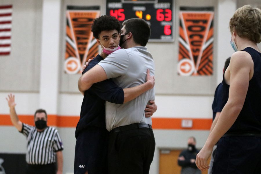 With a minute left of the game, junior Adrian Dimond goes off the court to hug head coach Kurt Bangle. 