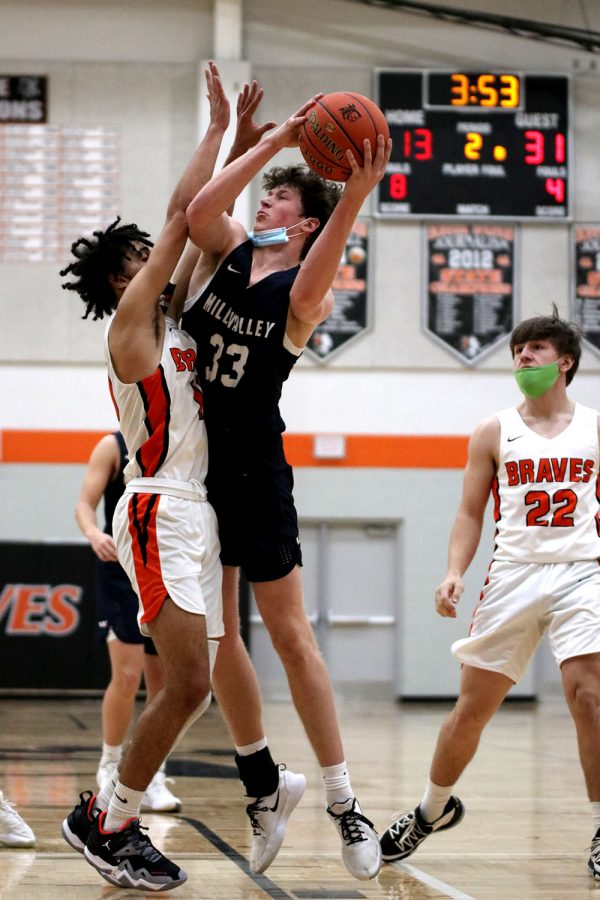 With his eyes on the basket, sophomore Dylan Blazer reaches over his opponent with the ball in his hands to score two points.