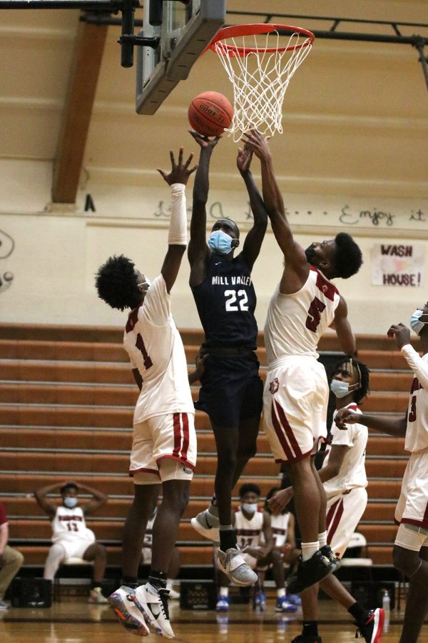 Between two opponents, sophomore Nen Matlock jumps up into the air to make a two pointer. 