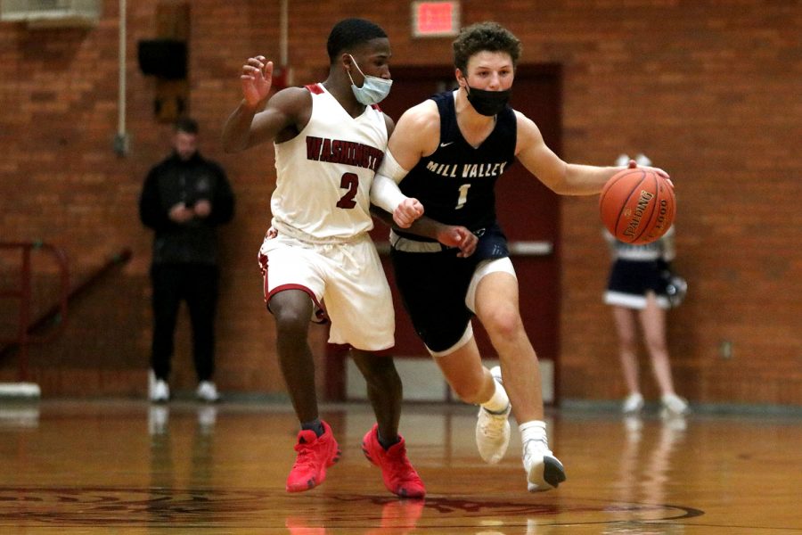 Blocking his opponent from grabbing the ball from him, senior Nick Mason dribbles the ball down the court Tuesday, March 9. The game ended with a final score of 52-47 with a victory for Washington and an end for the boys basketball team post-season.