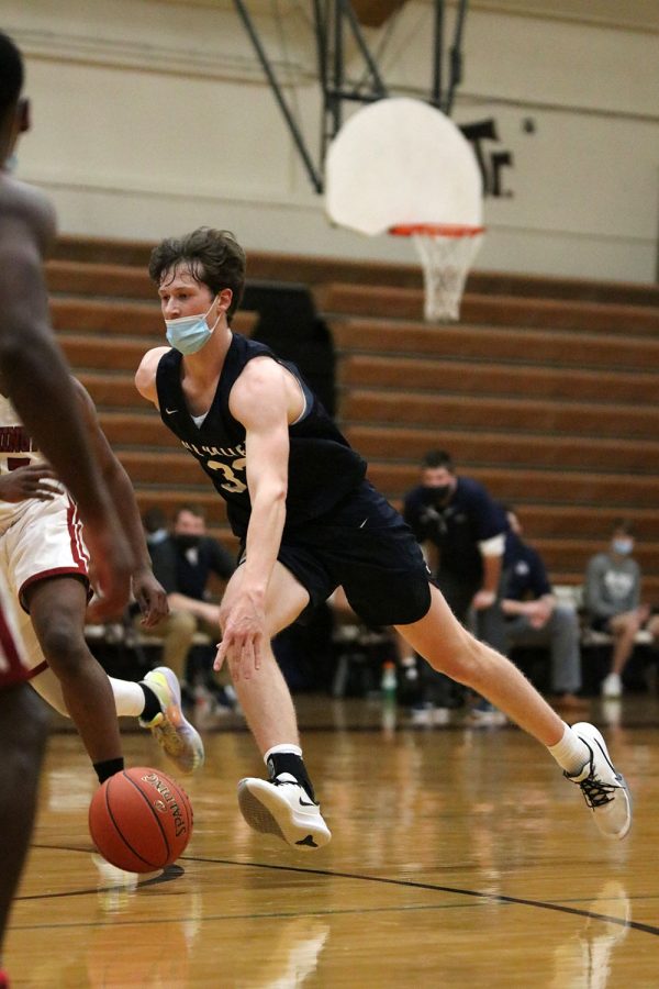 Dribbling around his opponent, sophomore Dylan Blazer attempts to get closer to the basket. 