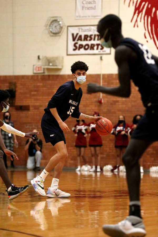 Looking at sophomore Nen Matlock, junior Adrian Dimond dribbles the ball.