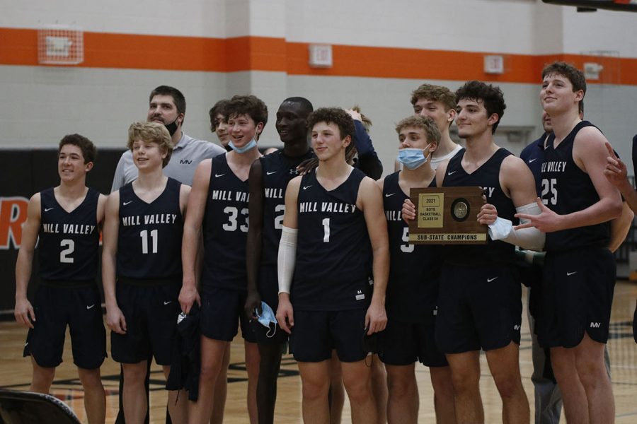 With the sub-state championship trophy in hand, the boys basketball team smiles for a group picture Saturday, March 6.