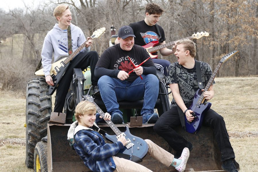 Holding their instruments, sophomore Anthony Molinaro and his band “Holiday Drive” pose for a picture while sitting on a tractor during band practice Thursday, Feb. 25. The band practices most Sundays. “The practices consist of us playing covers, our own songs and messing around,” Molinaro said.