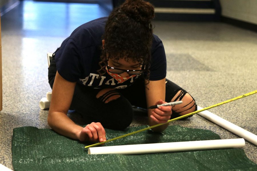 Using a marker, senior Alex Owens marks the correct measurement of where she needs to cut for the dog beds side post on the PVC pipe. 