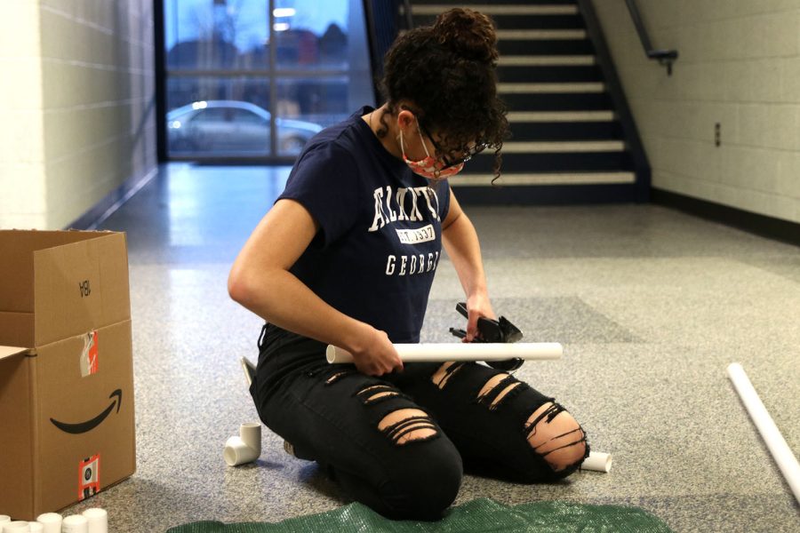 Using a PVC cutter, robotic team member senior Alex Owens cuts a piece of PVC pipe after measuring the correct length needed for the dog bed.