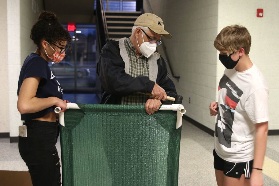 Hammering together PVC pipe, Robotics sponsor Gary Hannah helps robotics members senior Alex Owens and De Soto sophomore Julie Steeb make dog beds for non-profit animal shelter Imagine Forever Homes. The robotics team made dog beds on Thursday, March 4 at their weekly after school meeting.